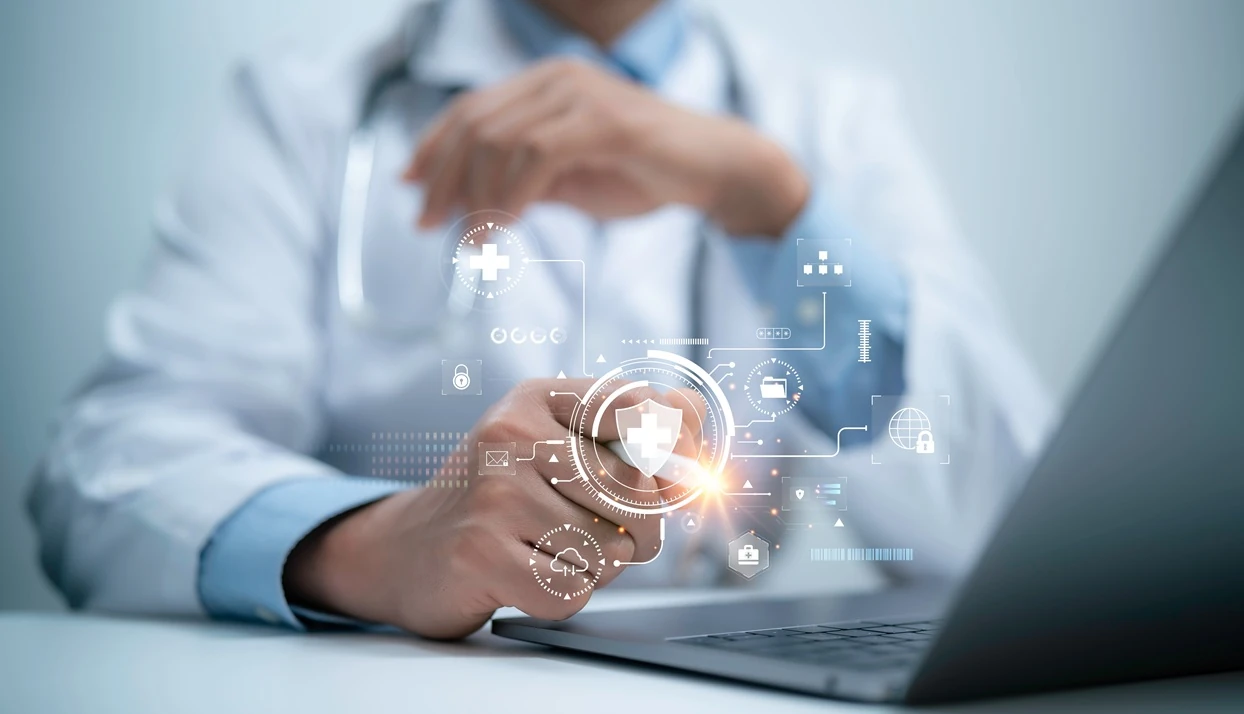 Healthcare professional using a laptop with digital health and security icons displayed