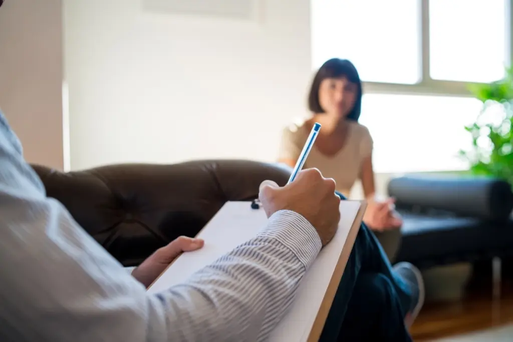A psychologist, an allied health professional, taking notes during a client consultation, illustrating the supportive role of Lyfe AI in enhancing mental health care.