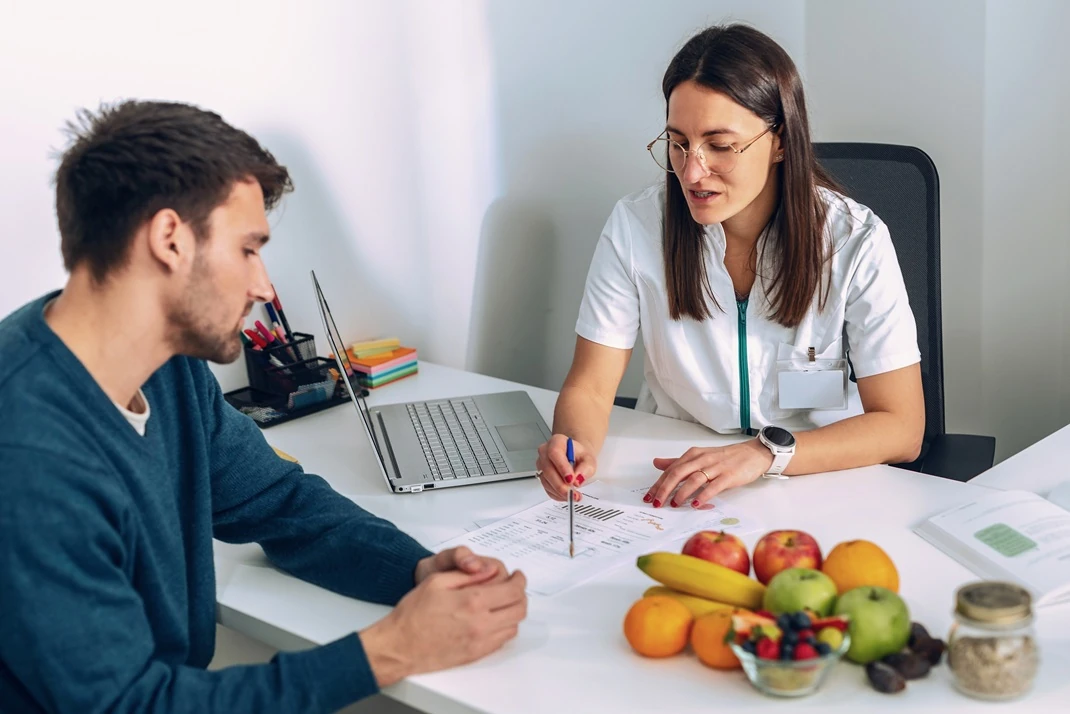 Nutritionist discussing health plans with a client at a desk with fresh fruits
