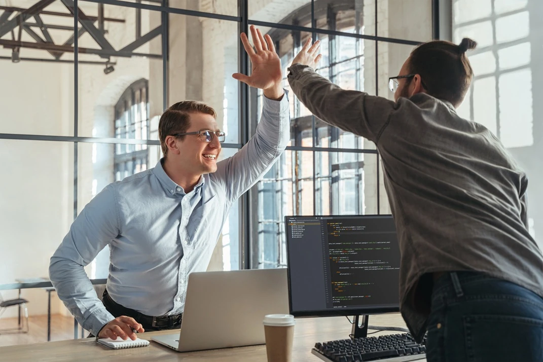 Two colleagues high-fiving in an office environment, celebrating success while using and partnering with LYFE AI solutions